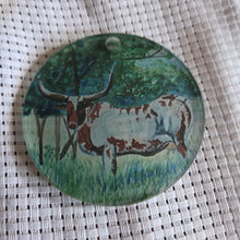 Load image into Gallery viewer, Round translucent decorative ornament featuring a bold longhorn design on a textured white background.