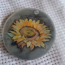 Load image into Gallery viewer, Round translucent decorative ornament featuring a bold sunflower design on a textured white background.
